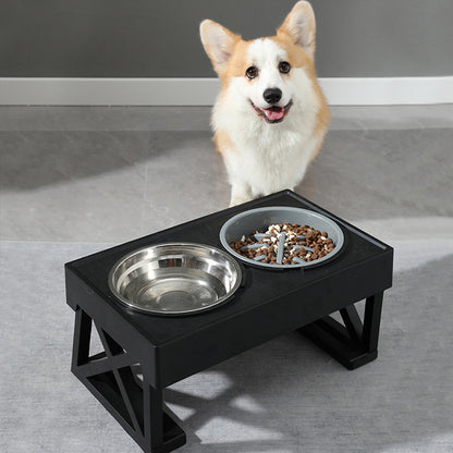 Dog standing next to a black elevated pet feeder with two bowls on a gray floor.